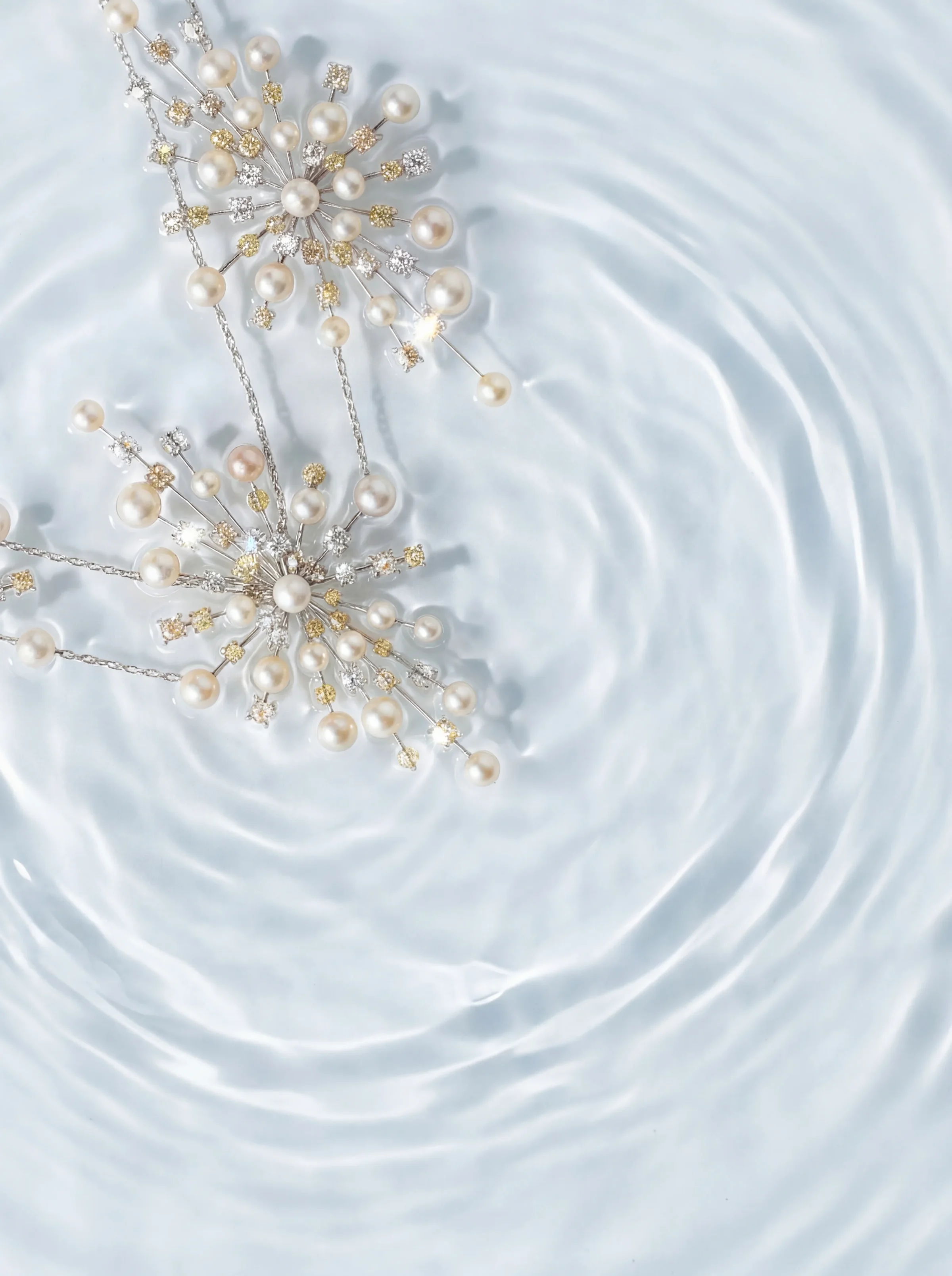 Pearl starburst necklace flat lay with water ripples